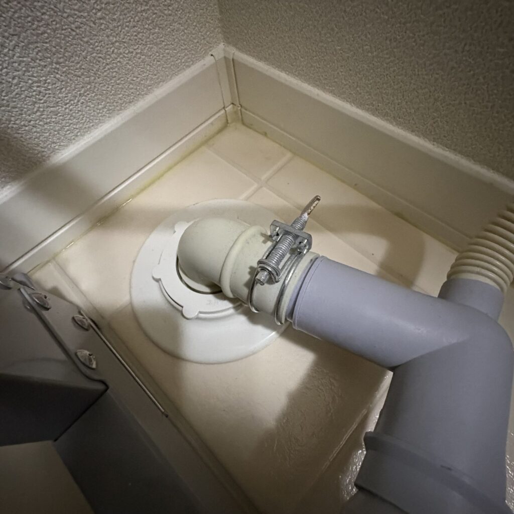 床下排水口と、L型排水継ぎ手を接続している様子