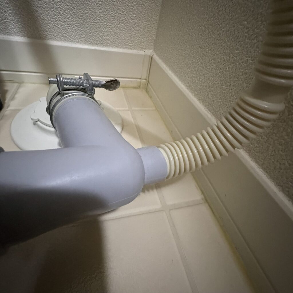 乾燥機の排水ホースとL型排水継ぎ手をつなげている様子。