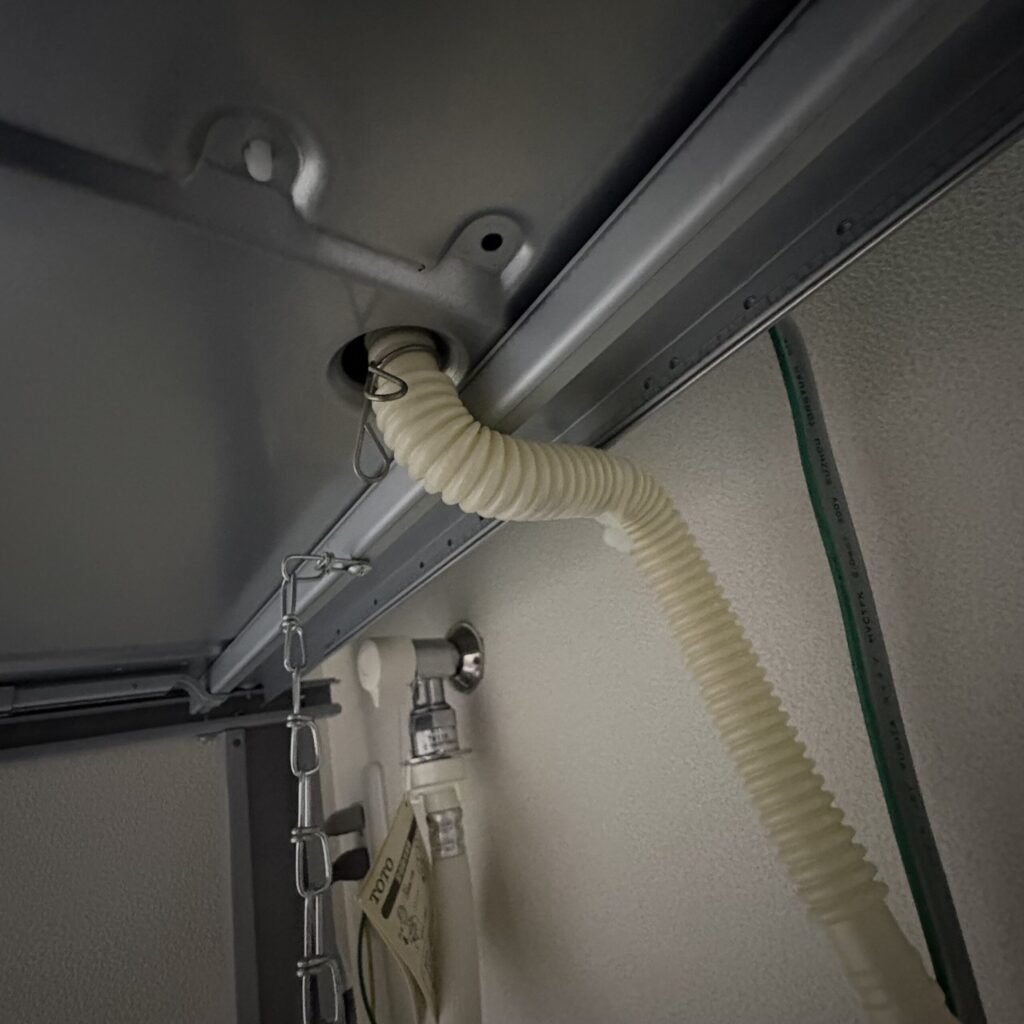 衣類乾燥機の排水ホースのスタートの写真。結束バンドで背面に行くよう固定している様子。