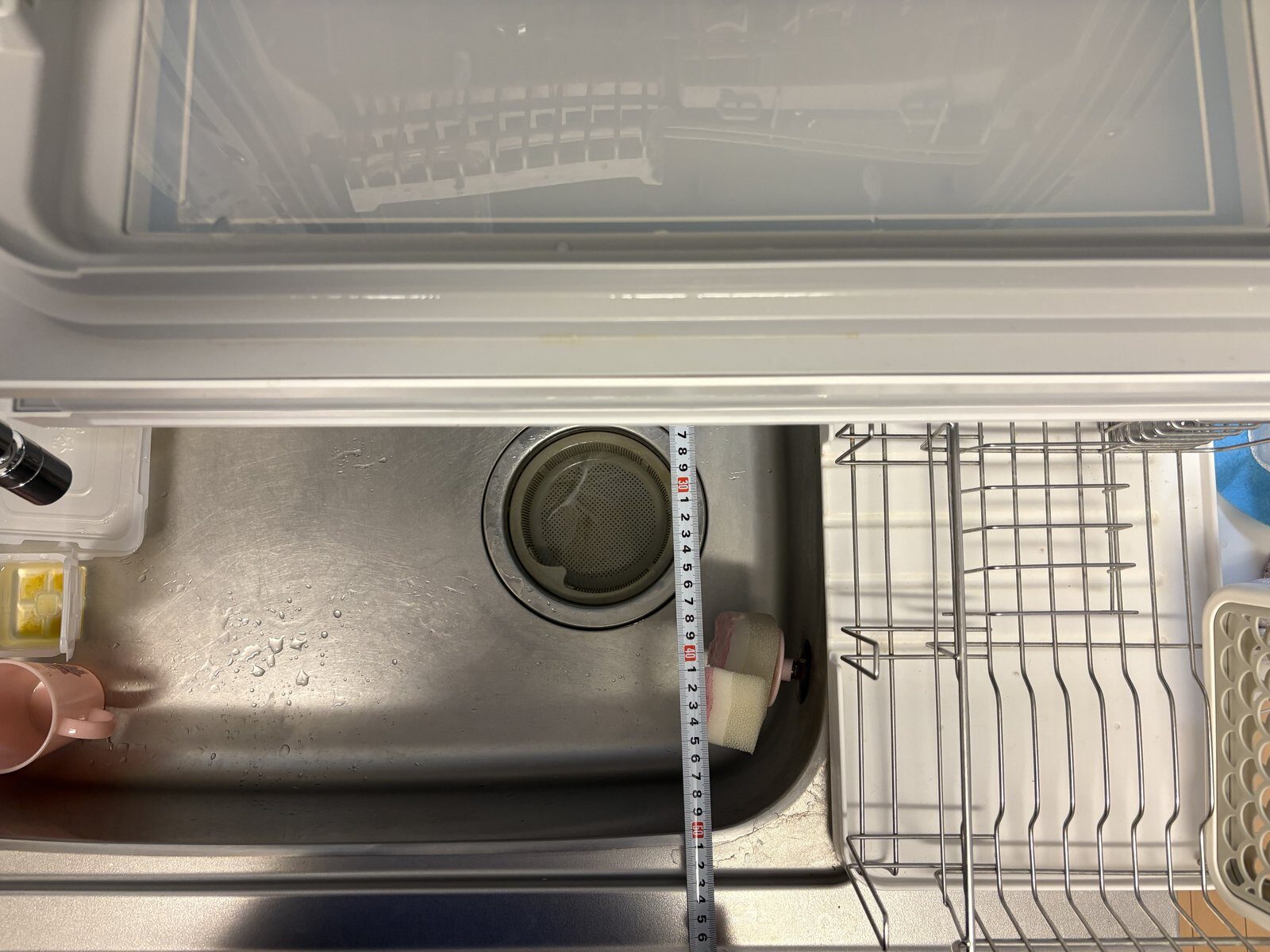 卓上食洗機の扉を開いた状態。シンク側にせり出している様子をメジャーで計測
